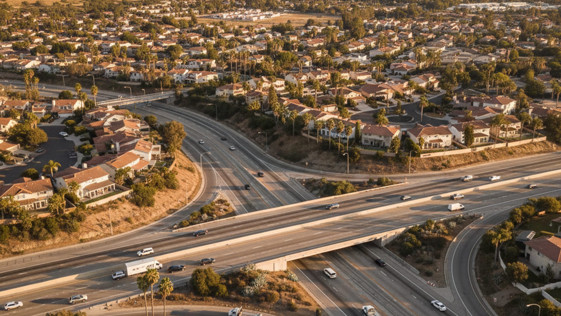 Elevated view of a freeway interchange running between suburban neighborhoods at golden hour